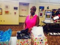 Woman in pink top smiles behind a table with gift boxes.