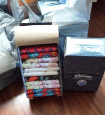 A tissue dispenser holding folded colorful cloth tissues, next to a Kleenex box.