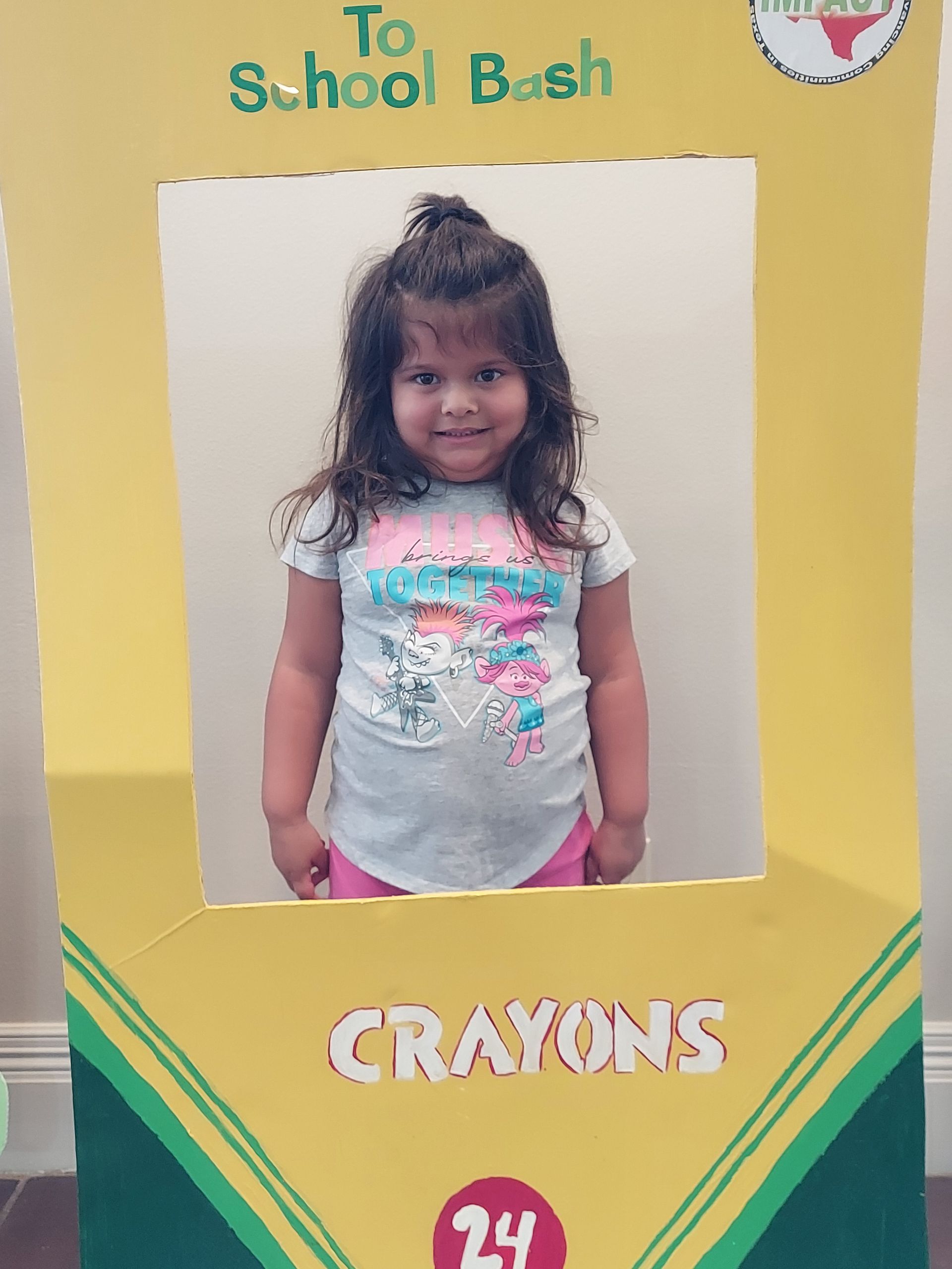 Girl poses in a crayon-themed photo frame at a 