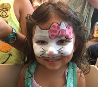 Girl with Hello Kitty face paint smiles at the camera.