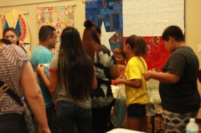 People gathered in a room with Texas flag art; some are holding items.