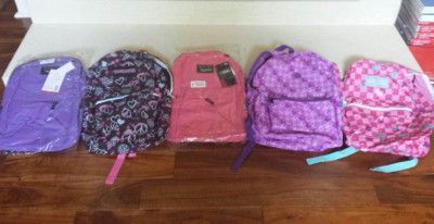 Five colorful backpacks lined up on a wooden floor, ready for school.