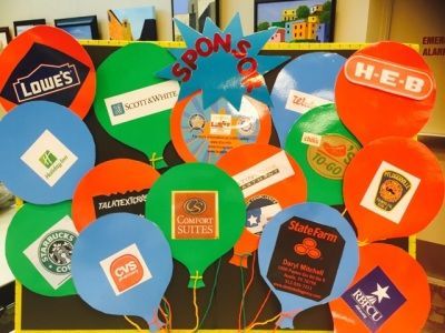 Sponsor display with colorful balloon cutouts, each displaying a business logo. 