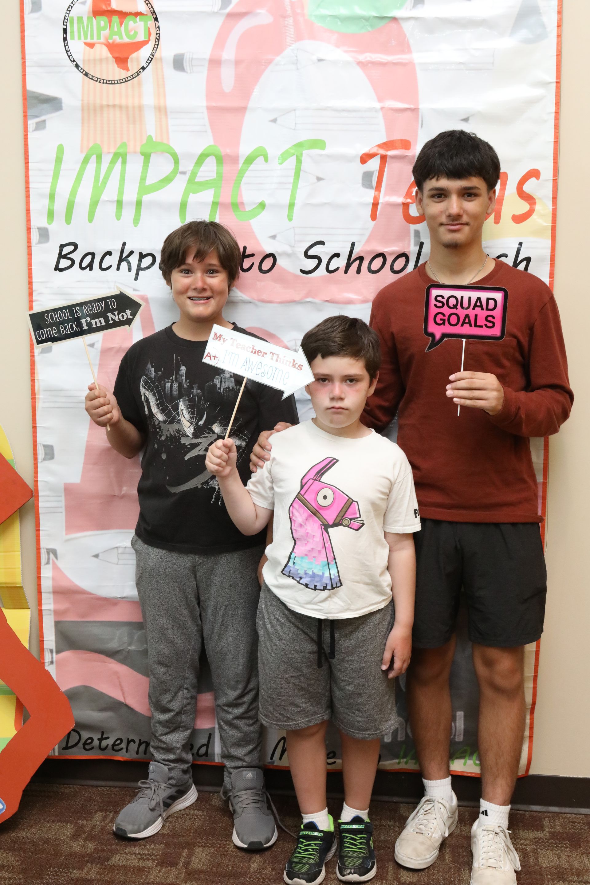 Three people holding signs in front of a banner that reads 