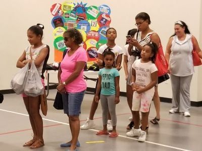 People standing near a colorful bulletin board in a gymnasium.