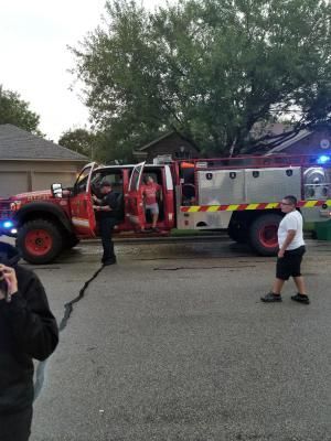 Fire truck with firefighters, one person exits; people on street.