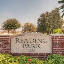 Reading Park sign on brick pillars, set among green shrubs and trees.