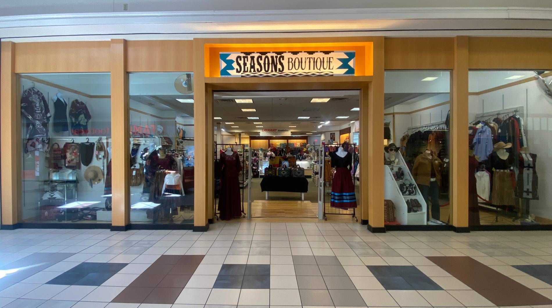 Storefront entrance with glass doors and windows, displaying clothing inside and a sign above the entrance.