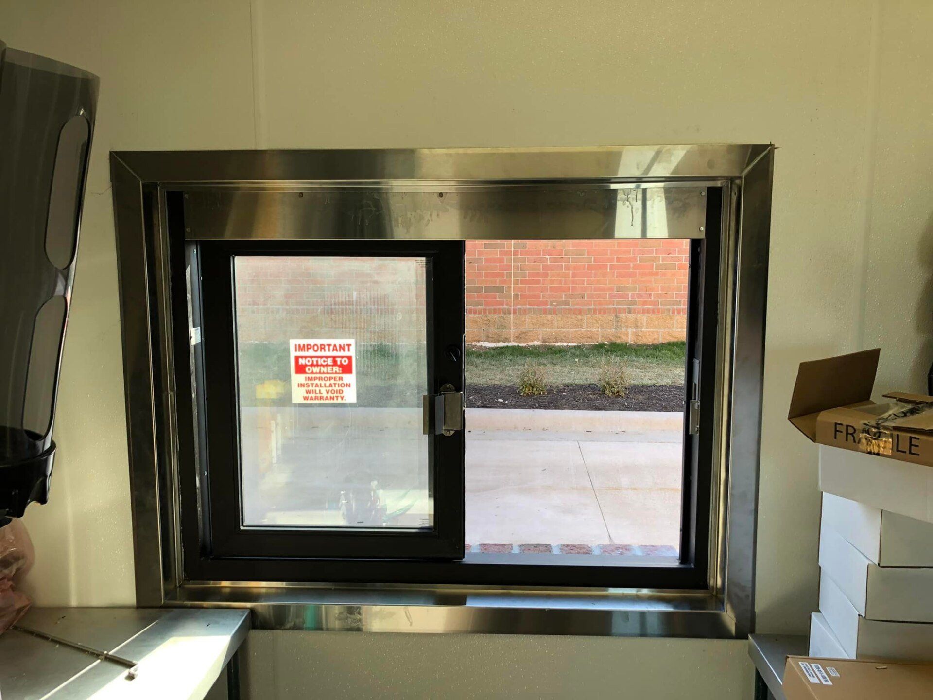 A stainless steel window in a kitchen with a brick wall in the background.