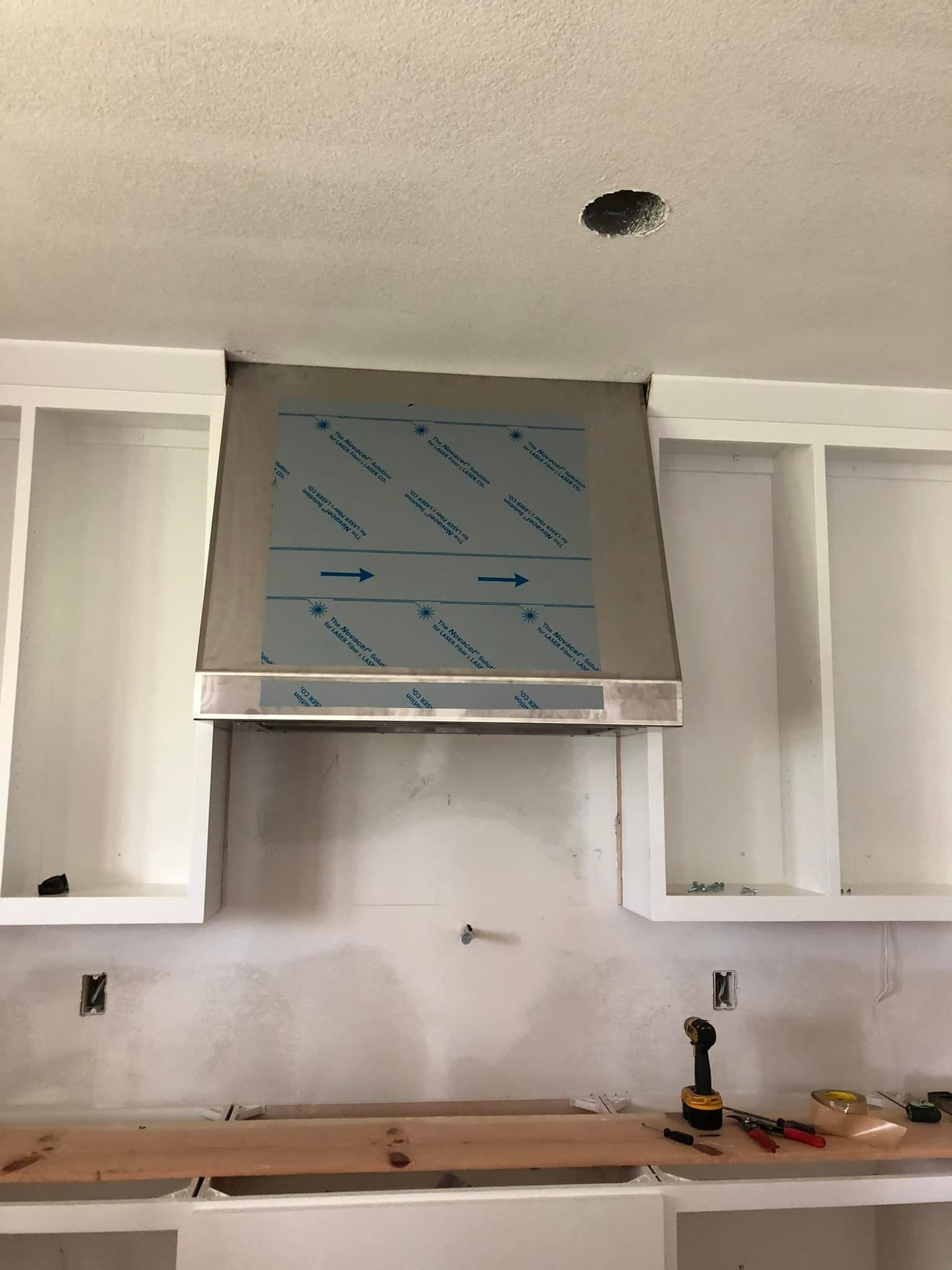 A kitchen with white cabinets and a stainless steel hood.