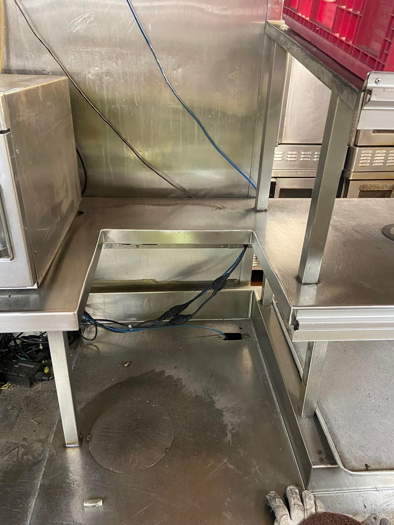 A stainless steel shelf with a microwave on top of it in a kitchen.