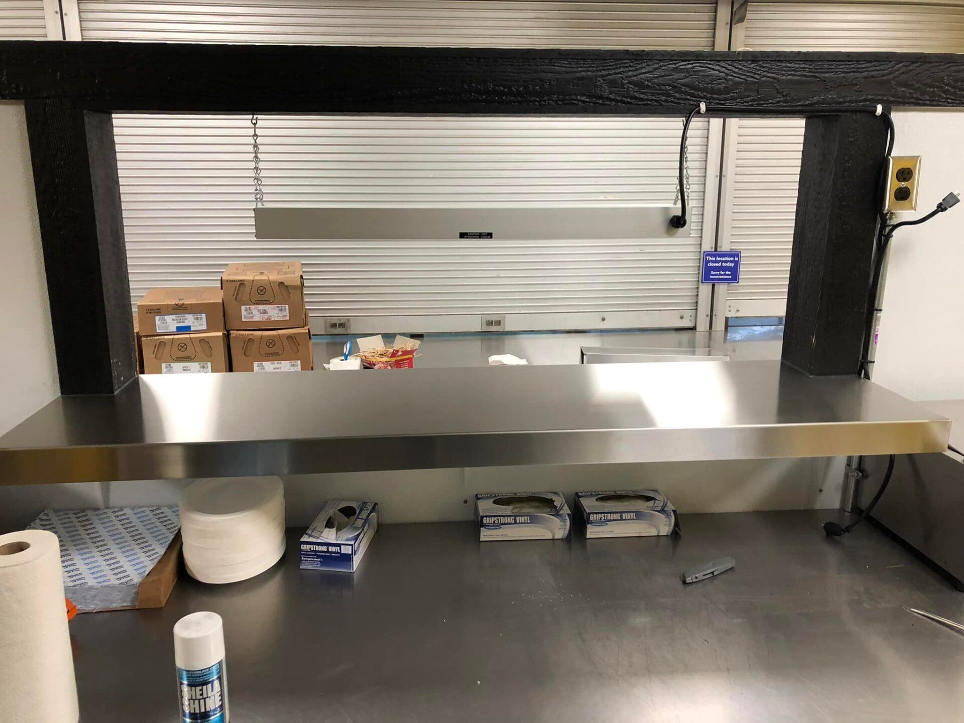 A stainless steel counter top in a kitchen with paper towels and gloves on it.