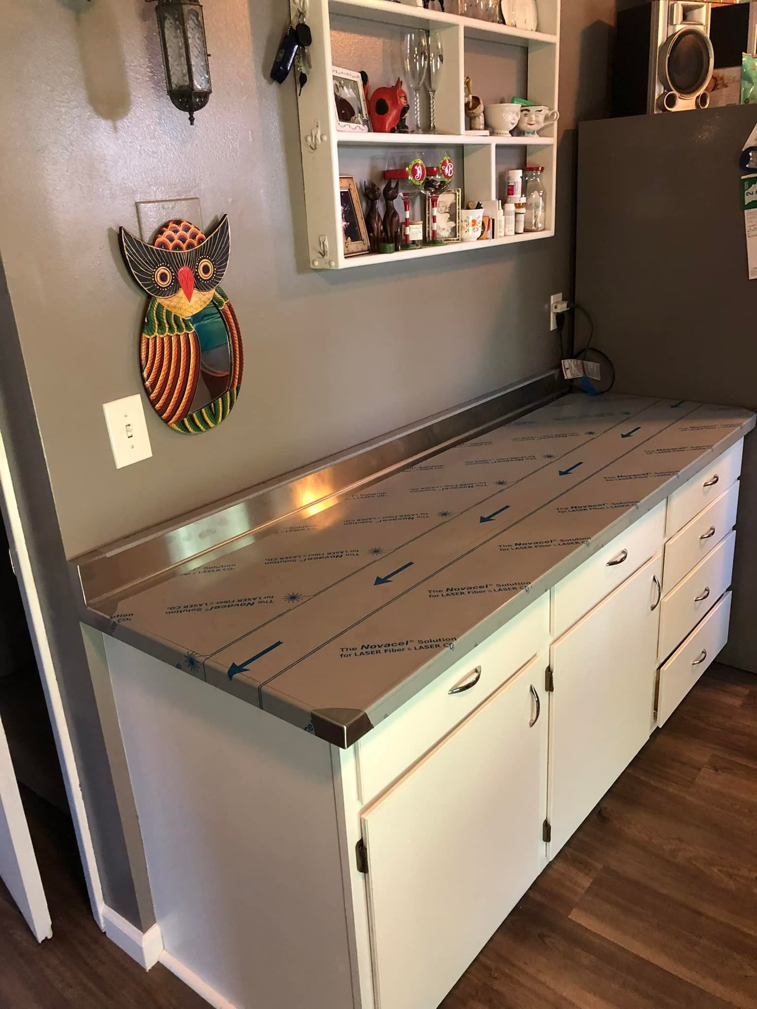 A kitchen with a stainless steel counter top and white cabinets.