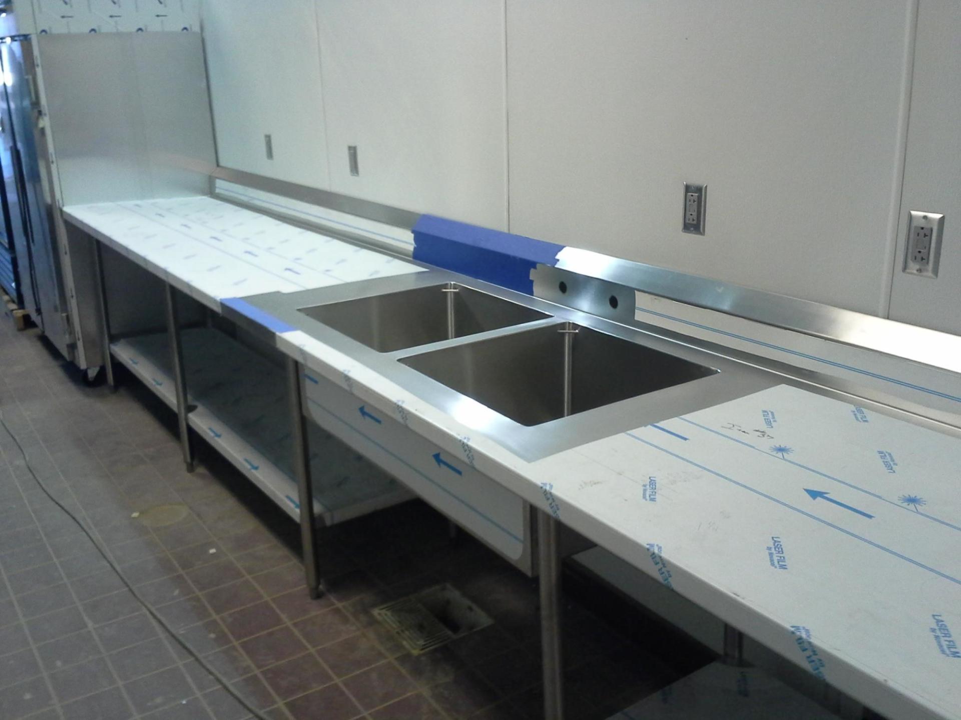 Two stainless steel sinks on a counter in a kitchen