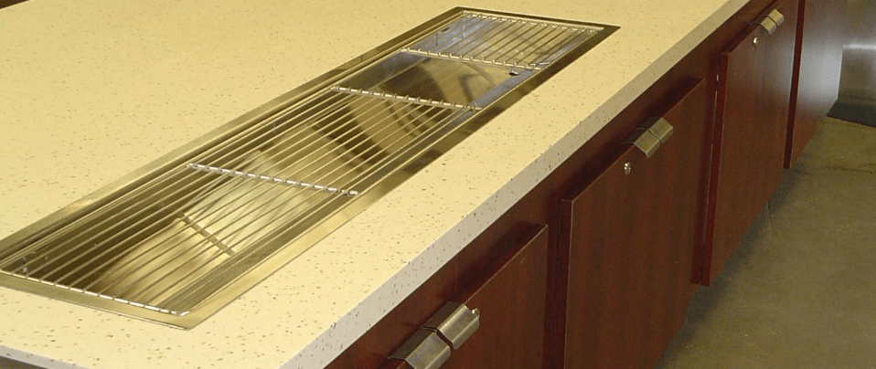 A kitchen counter with a stainless steel sink and wooden cabinets