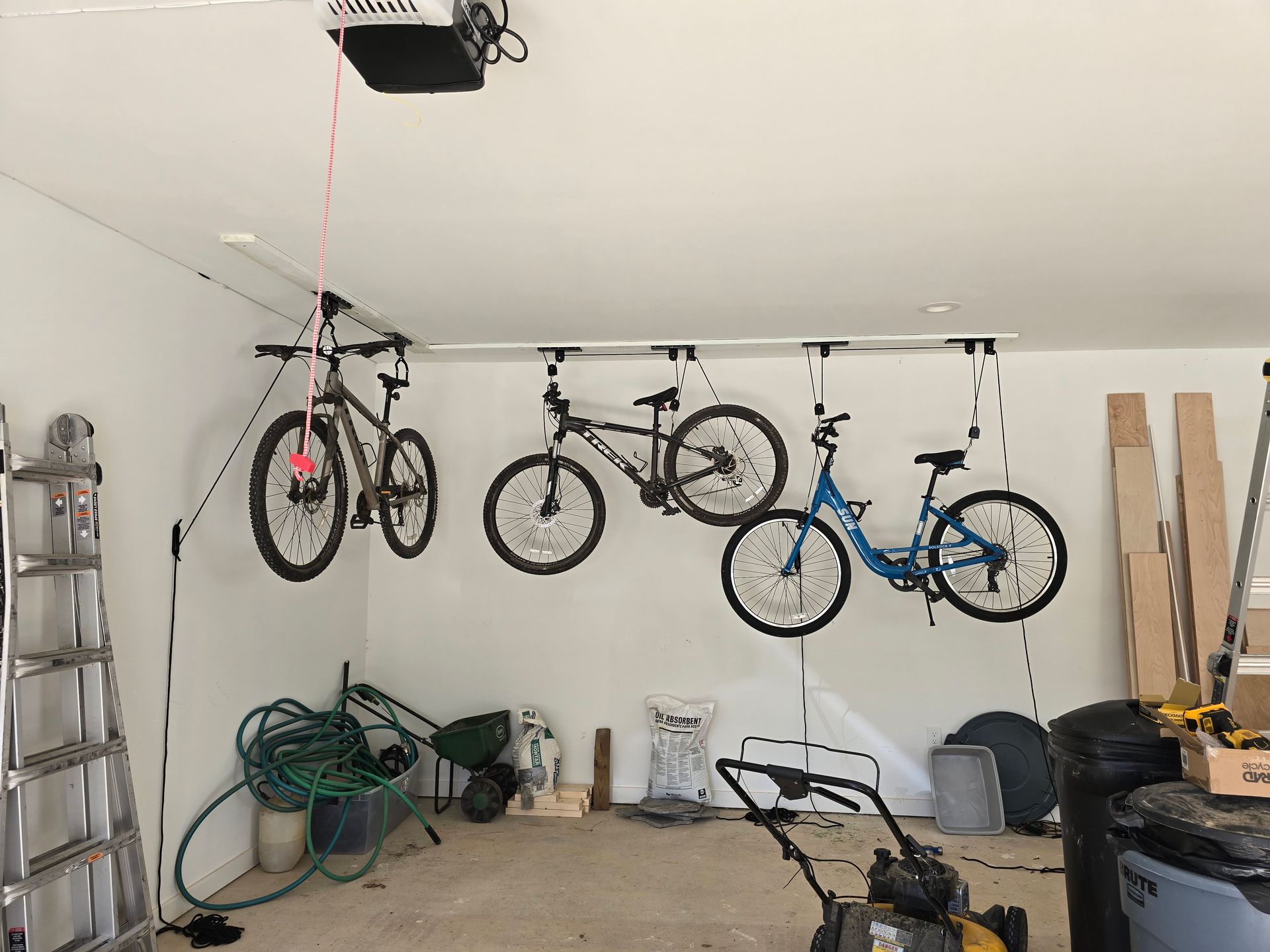 Garage with bicycles suspended from a ceiling-mounted storage system.