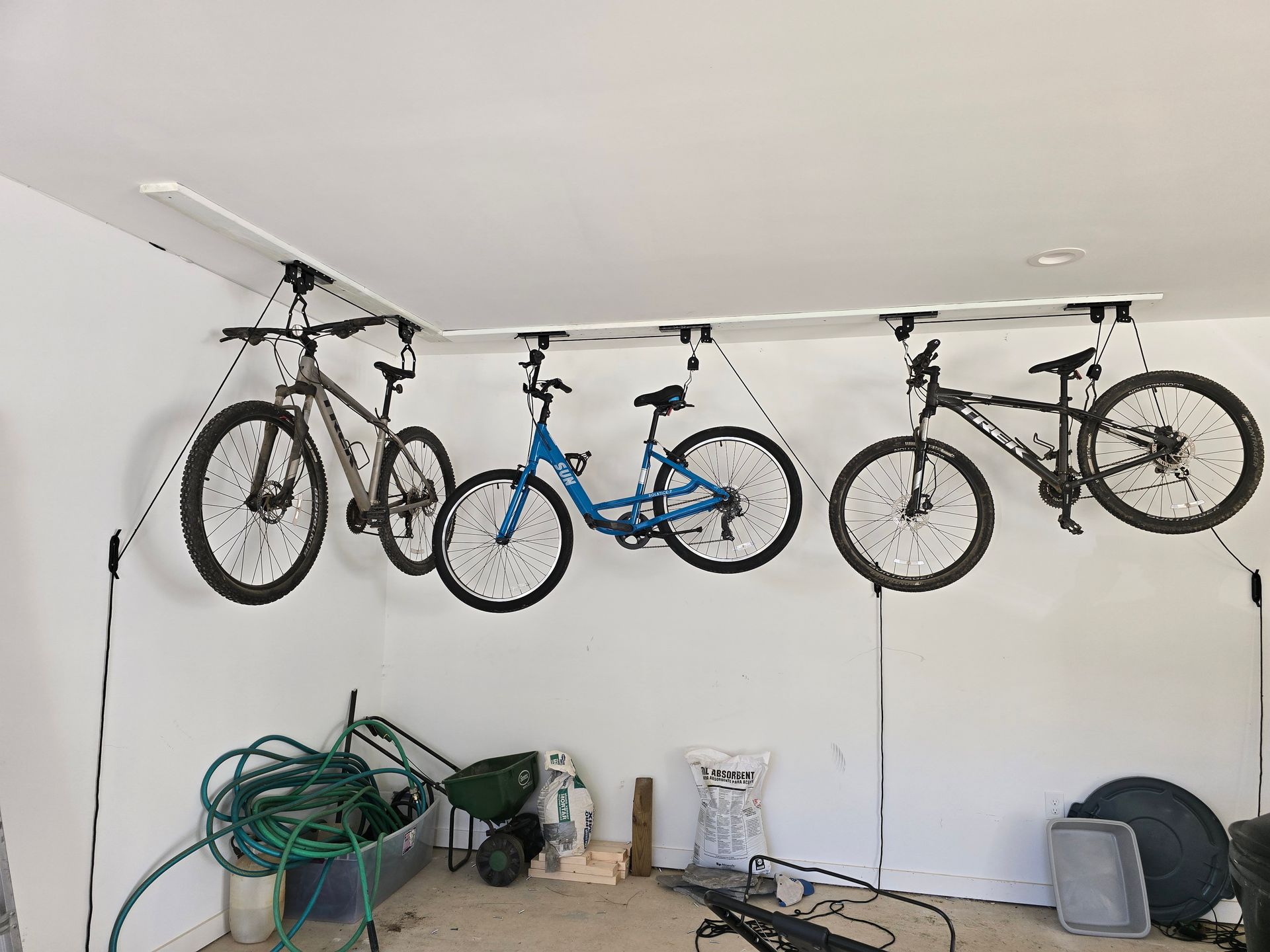 Four bikes suspended from a ceiling-mounted rack in a garage.