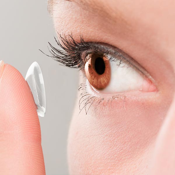 Contact Lenses — Woman Inserting a Contact Lens in Eye in Lawton, OK