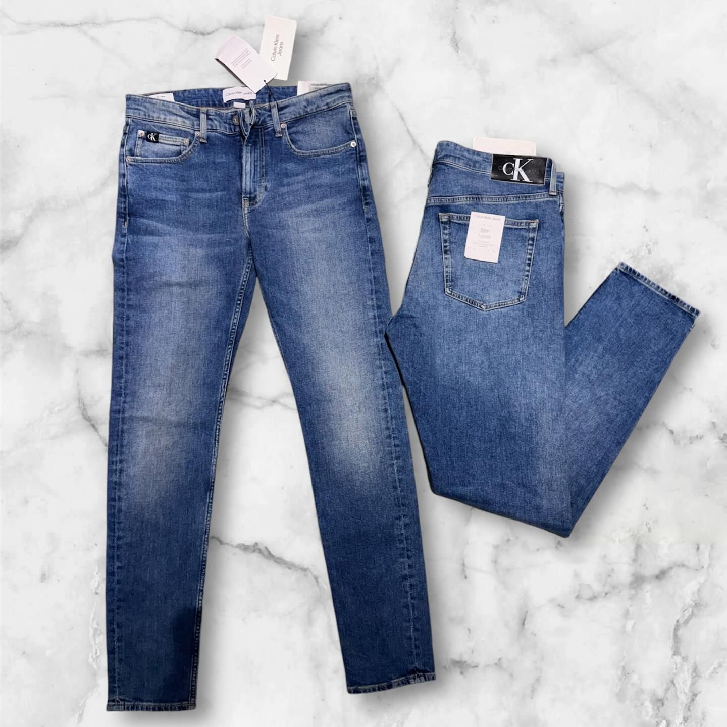 Un paio di jeans Calvin Klein adagiati su una superficie di marmo