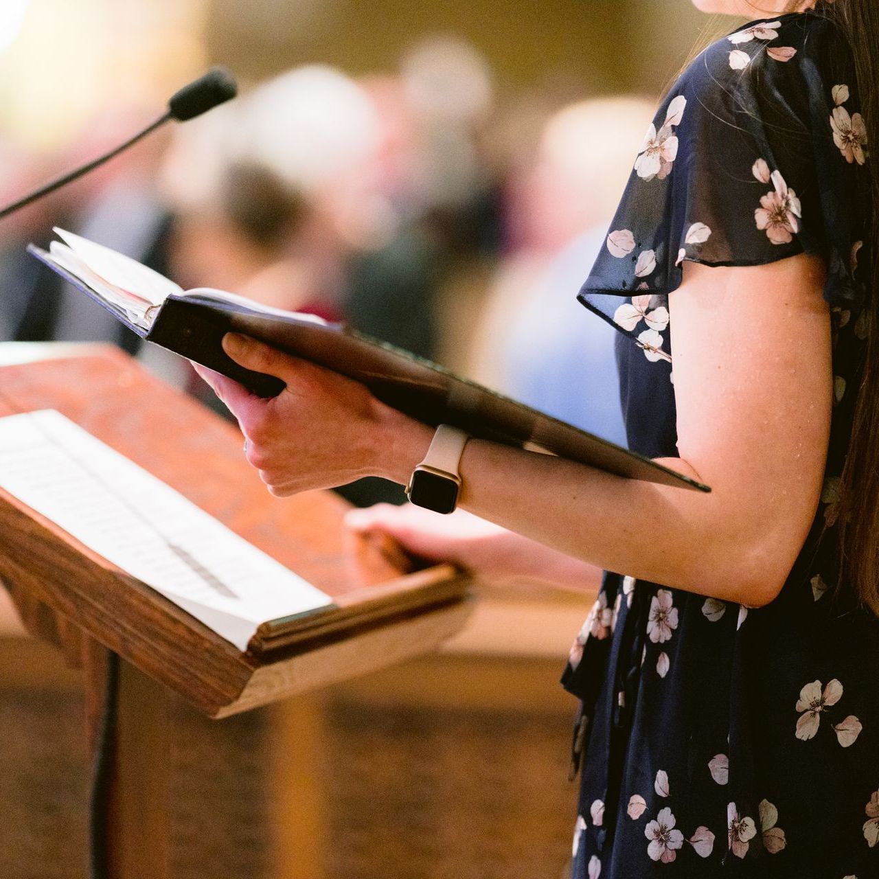 Person holding an open book at a lectern during a speech or reading