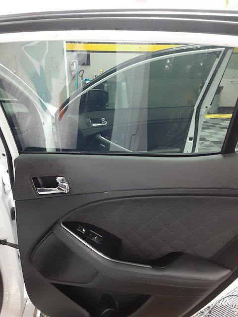 A white car with the door open is parked in a garage.