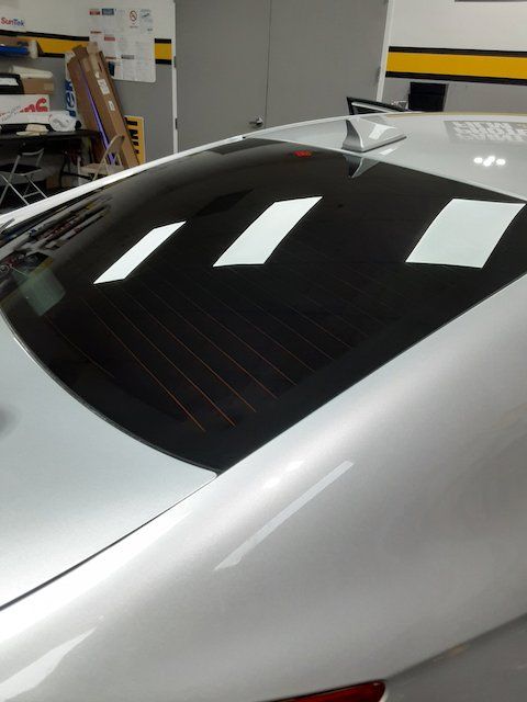 A silver car with a black roof is parked in a garage