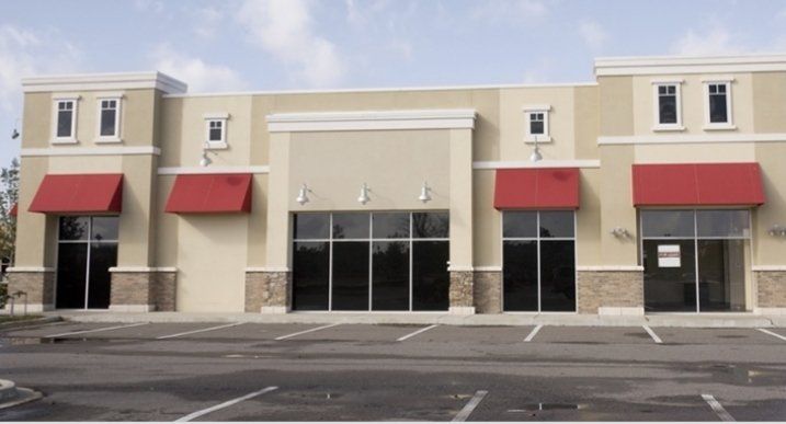 A building with red awnings and a parking lot in front of it