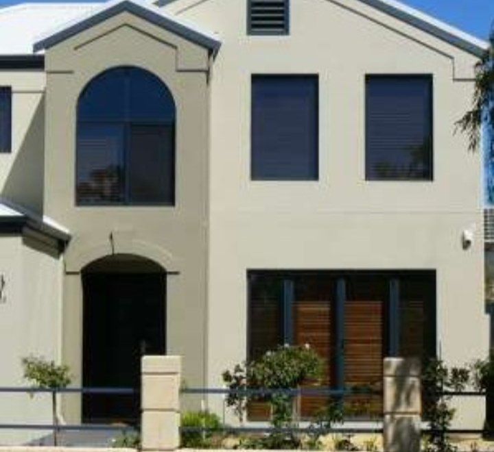 A white house with a lot of windows and a fence in front of it.