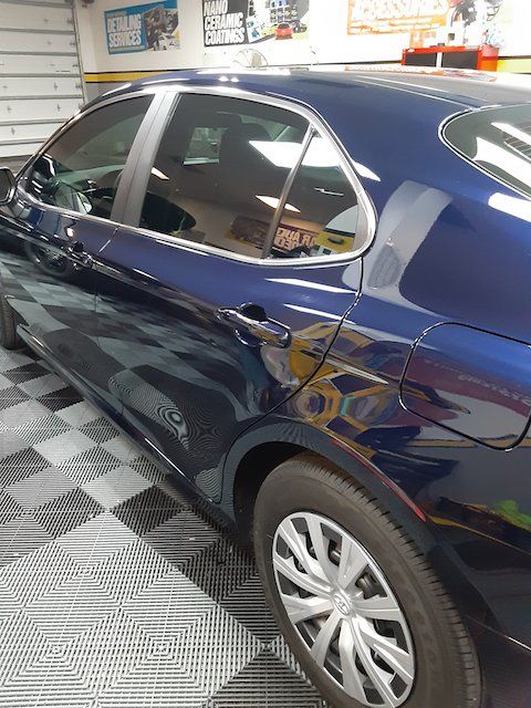A blue car is parked in a garage on a checkered floor.