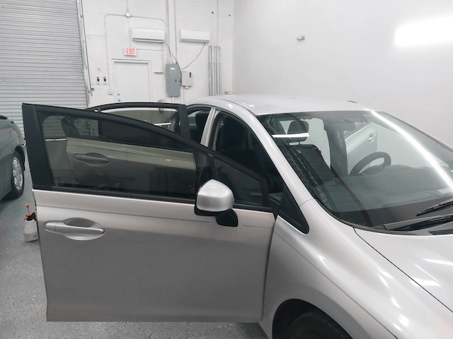 A silver car is parked in a garage with its doors open