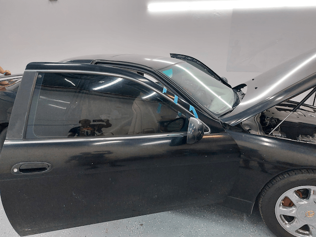 A black car with the hood up and the door open