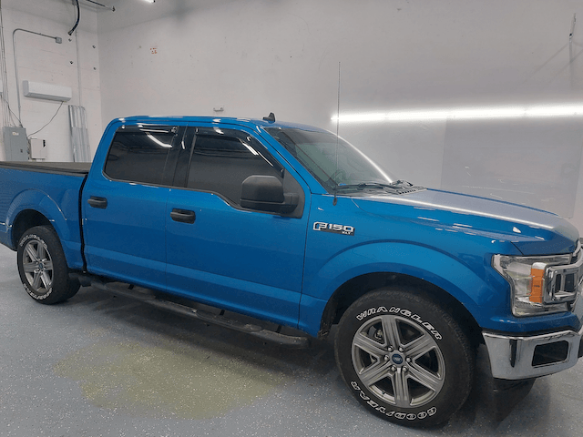 A blue ford f150 truck is parked in a garage.