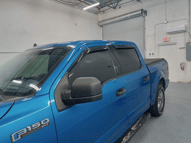 A blue ford f150 truck is parked in a garage.