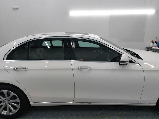 A white car is parked in a garage next to a white wall.