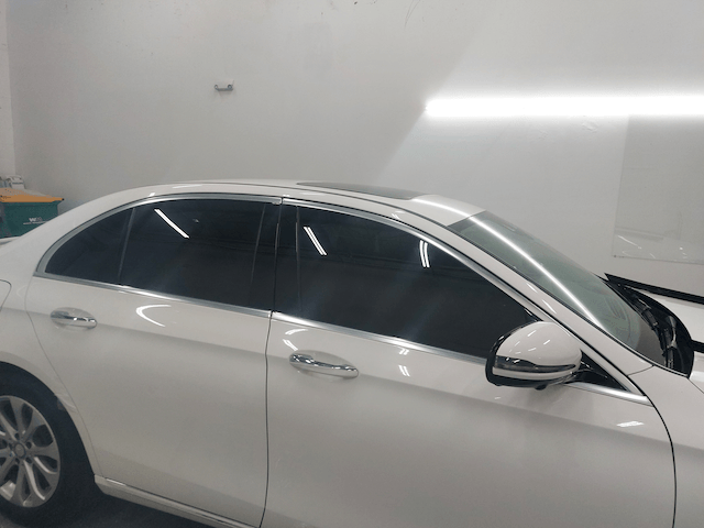 A white car with black windows is parked in a garage.