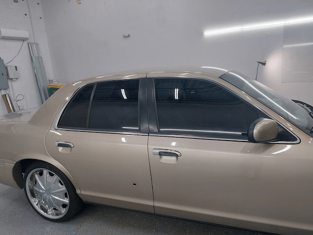 A tan car is parked in a garage with the hood up