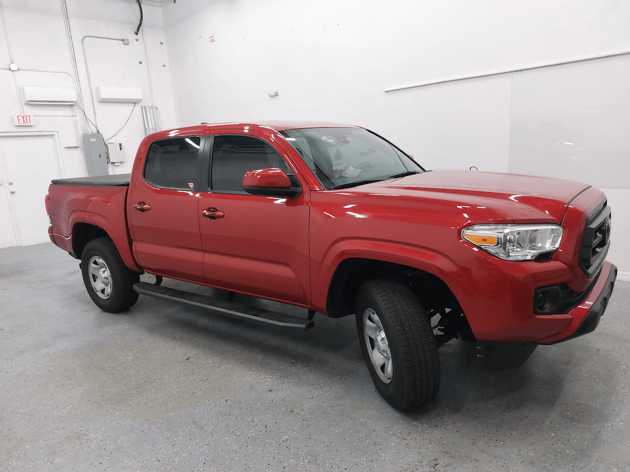 A red toyota tacoma truck is parked in a garage.