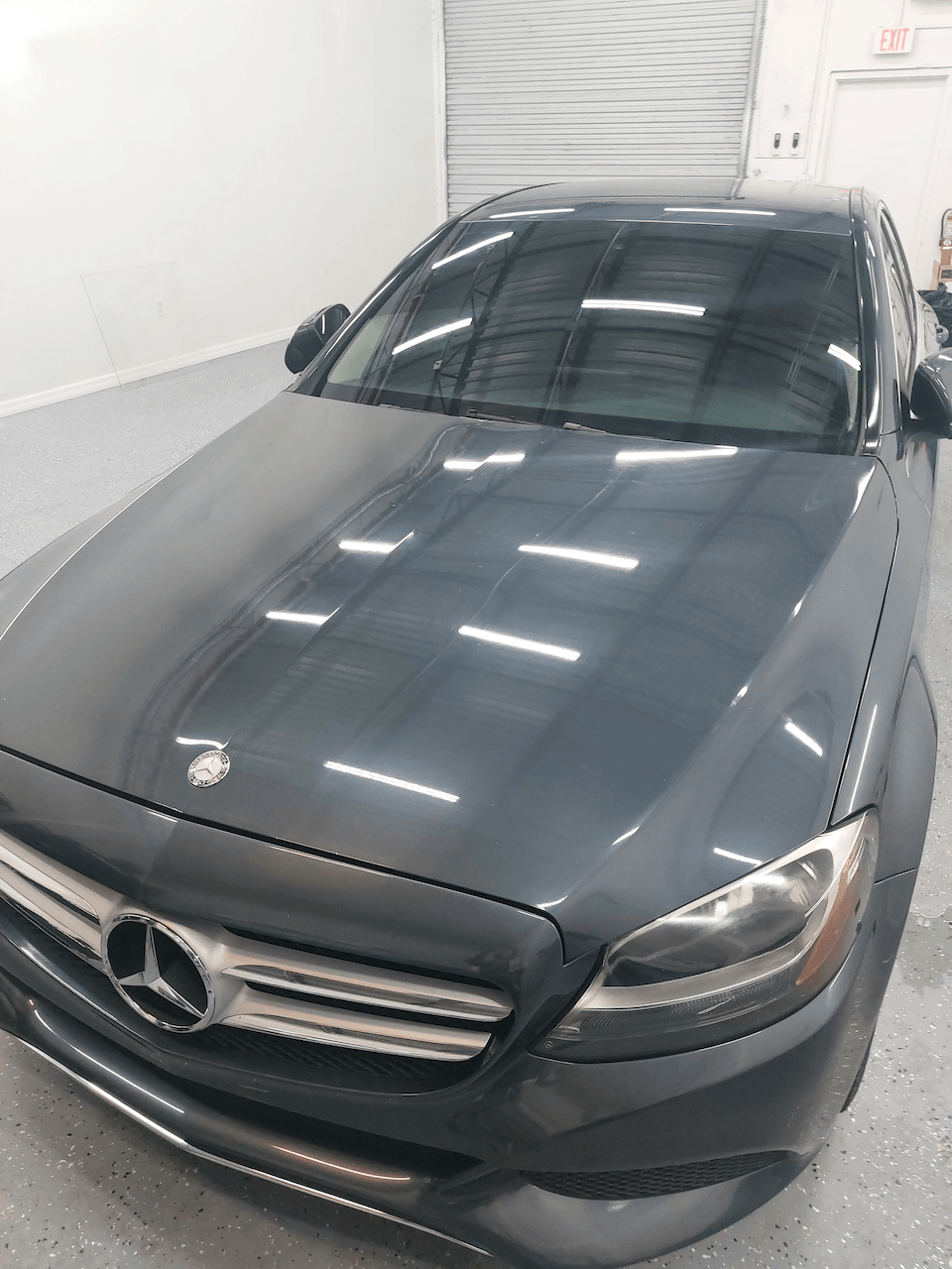 A black mercedes benz is parked in a garage.