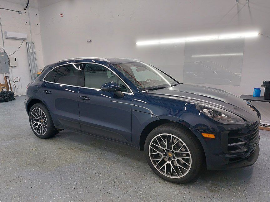 A blue porsche macan is parked in a garage.