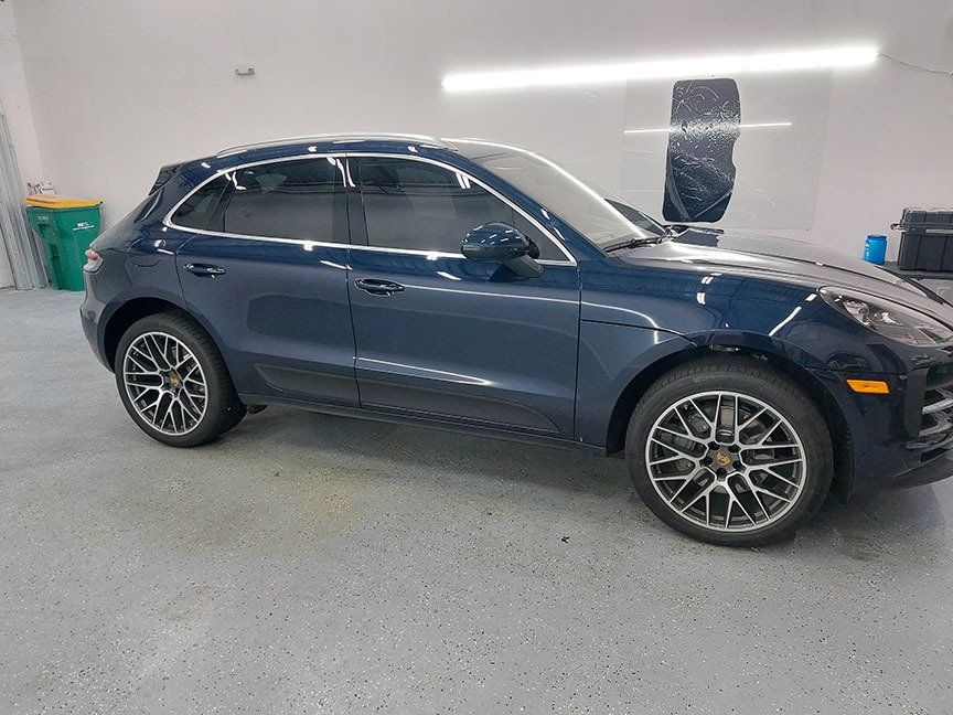 A blue porsche macan is parked in a garage.