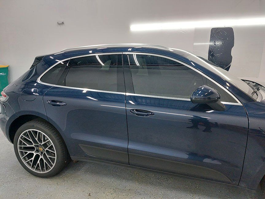 A blue porsche macan is parked in a garage.