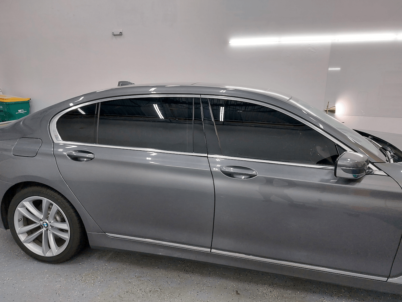 A gray car with tinted windows is parked in a garage.