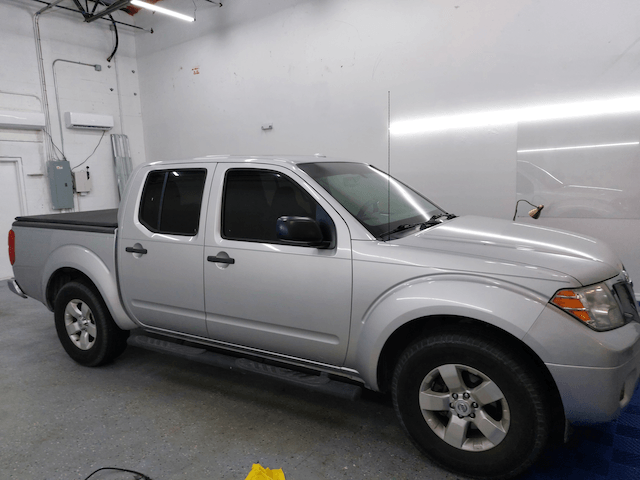 A silver pickup truck is parked in a garage
