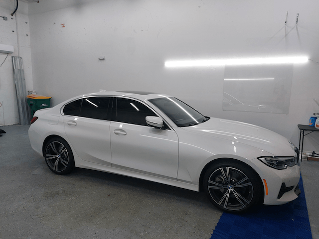 A white bmw 3 series is parked in a garage.