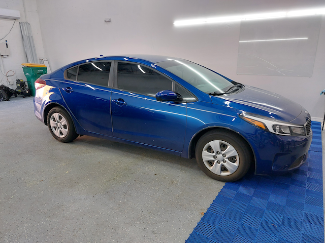 A blue car is parked in a garage.