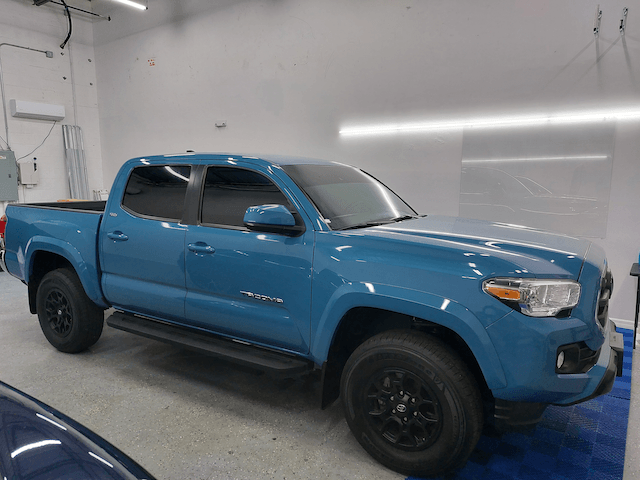 A blue toyota tacoma truck is parked in a garage.