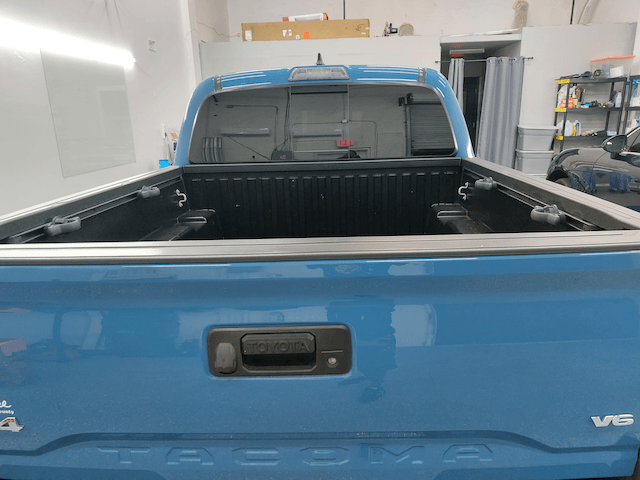 A blue toyota tacoma truck is parked in a garage.