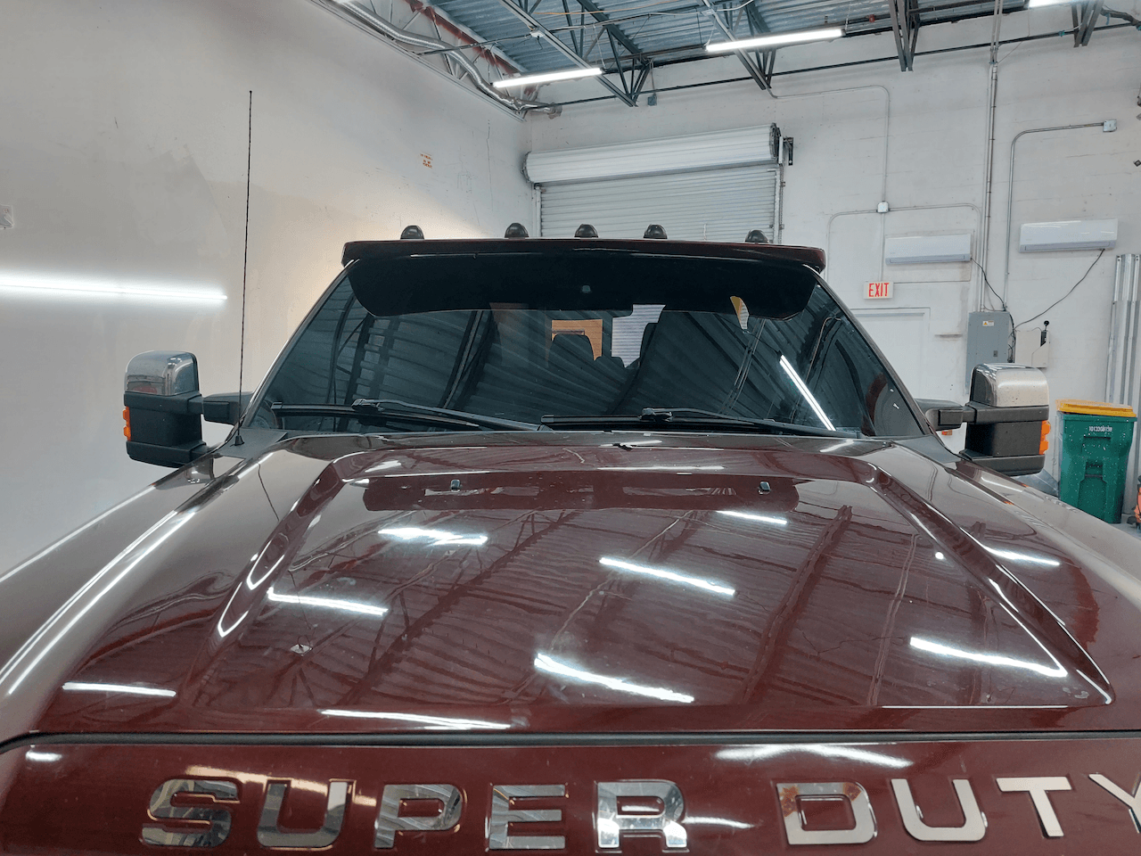 A red super duty truck is parked in a garage