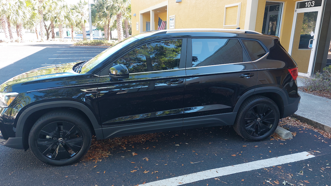 A black suv is parked in a parking lot in front of a building.