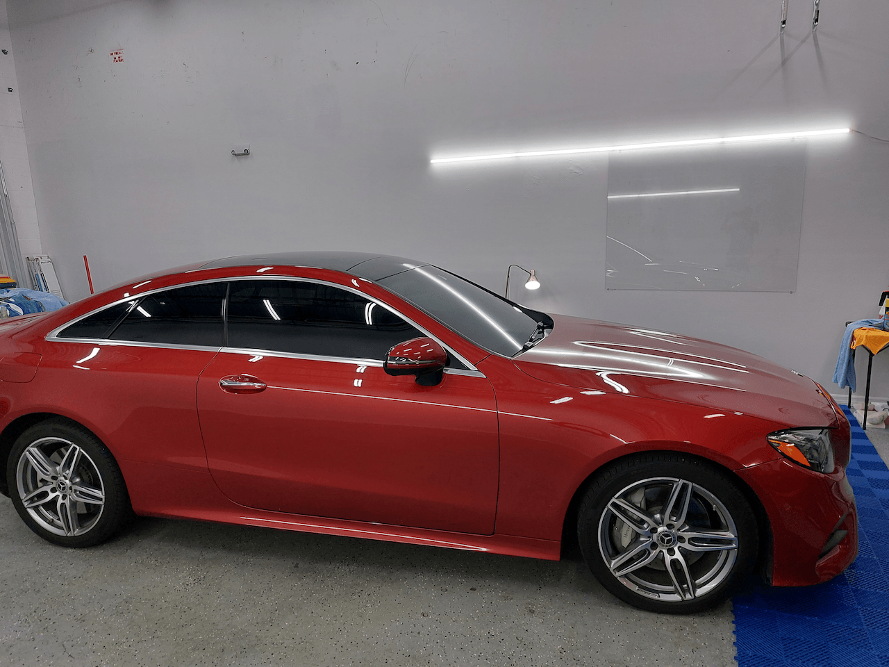 A red mercedes benz e class coupe is parked in a garage.
